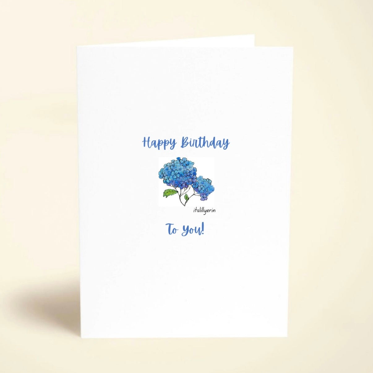 Greeting card with blue hydrangea illustration and 'Happy Birthday' text on a beige background